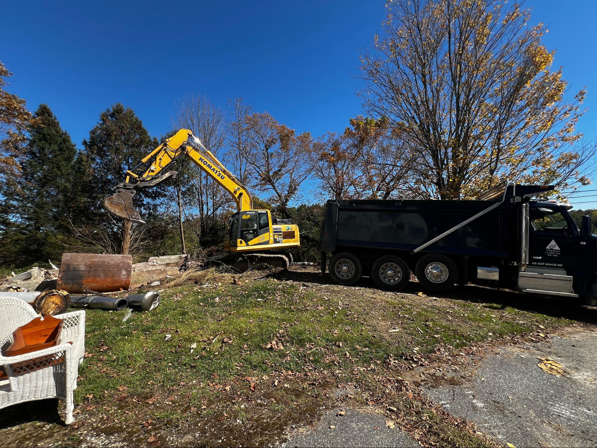Excavator loading demolition debris into dump truck